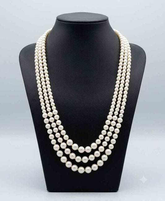 A multi-strand pearl necklace displayed on a black jewelry bust against a light gray studio background.
