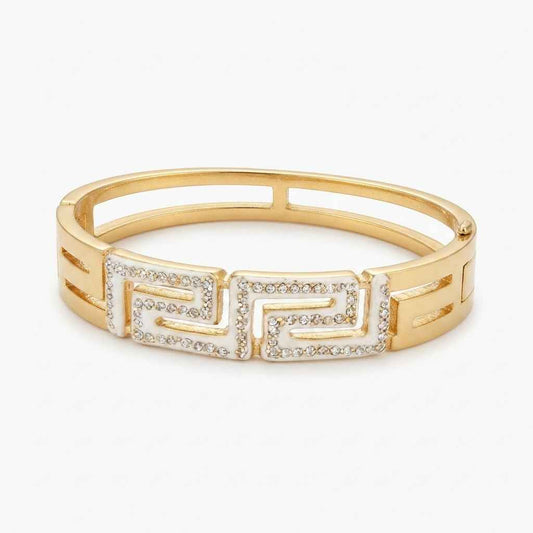 A gold-plated bangle bracelet featuring a Greek key pattern embellished with small clear rhinestones, set against a plain white background.