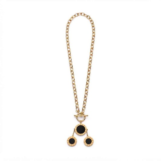A gold chain necklace with a toggle clasp and a pendant featuring three circular black inlays set in a textured gold frame, displayed on a solid white background.