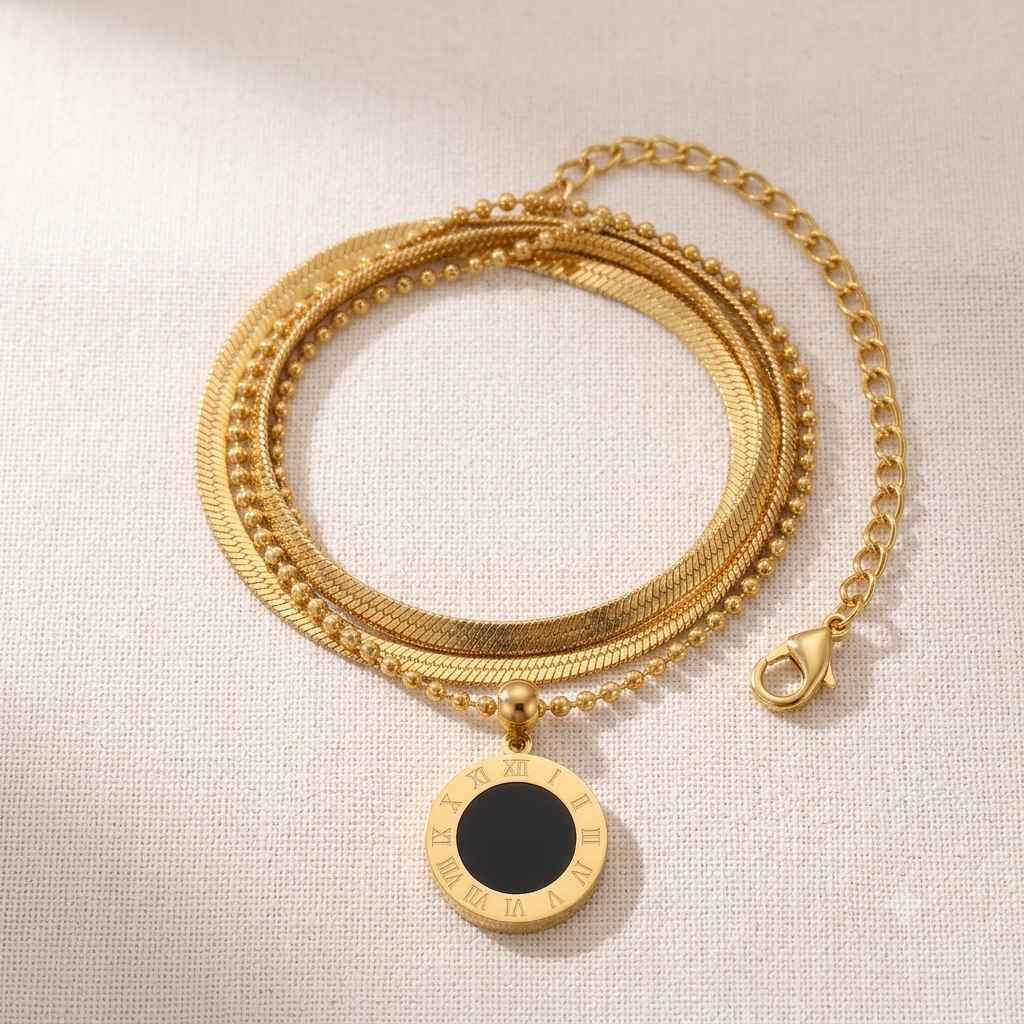 A gold-toned multi-strand chain necklace with a round pendant featuring a black center and Roman numerals, displayed on a textured beige fabric background.