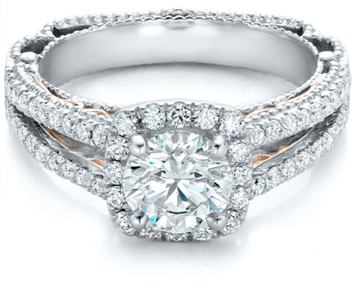 A double-band diamond ring featuring a large round-cut center stone surrounded by a halo, with smaller diamonds along the bands. The ring is set in a silver-toned metal with rose gold accents visible on the inner band, photographed on a clean white background.