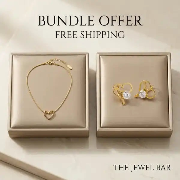 A jewelry bundle offer from The Jewel Bar featuring a gold heart-link bracelet and matching gold heart stud earrings with clear gemstones, presented in two beige satin boxes on a light marble background with 'BUNDLE OFFER FREE SHIPPING' text.